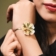 Woman wearing a gold bracelet on her wrist with a blurred background